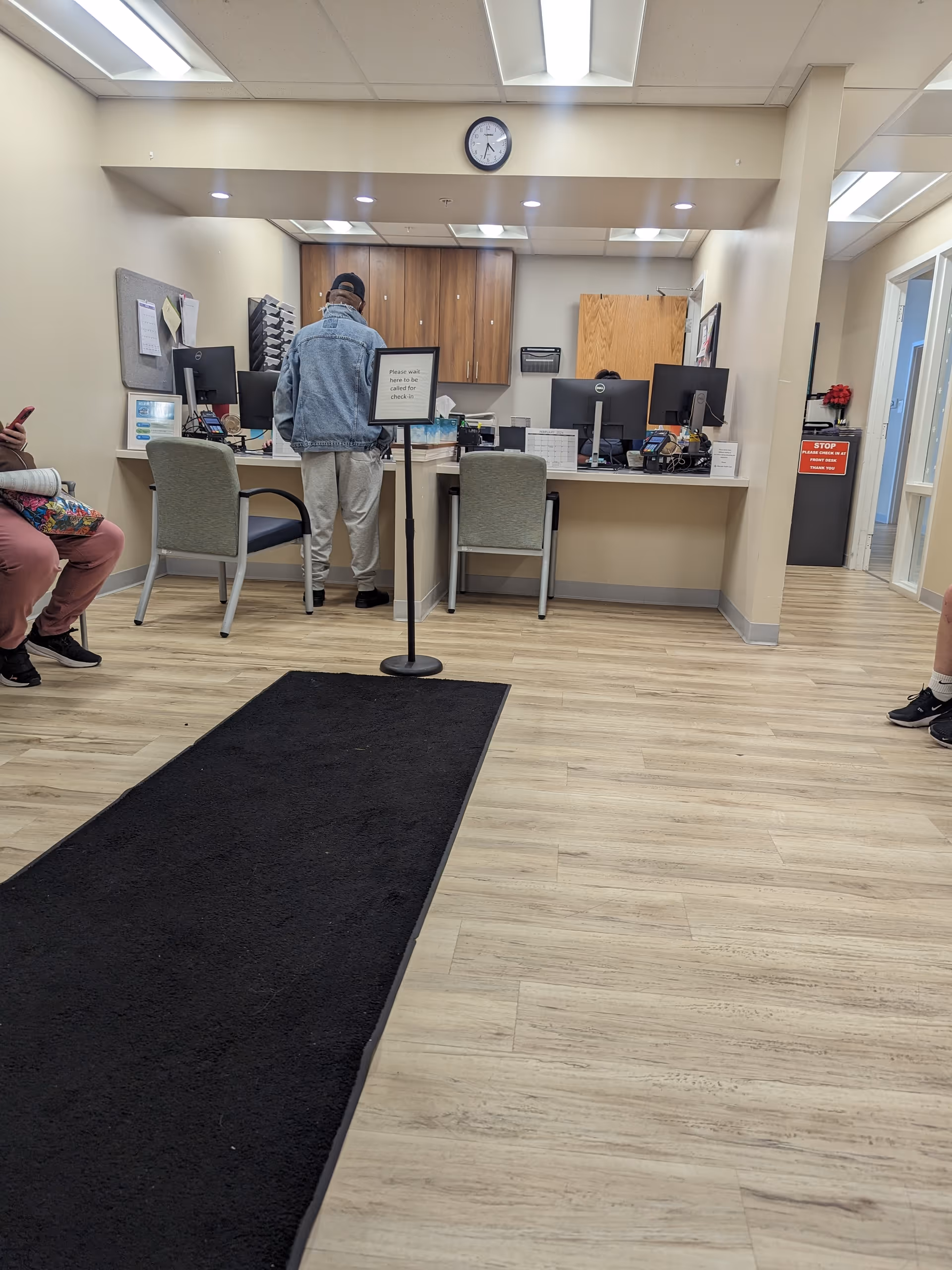 A reception area with a man at a counter and multiple computer workstations.