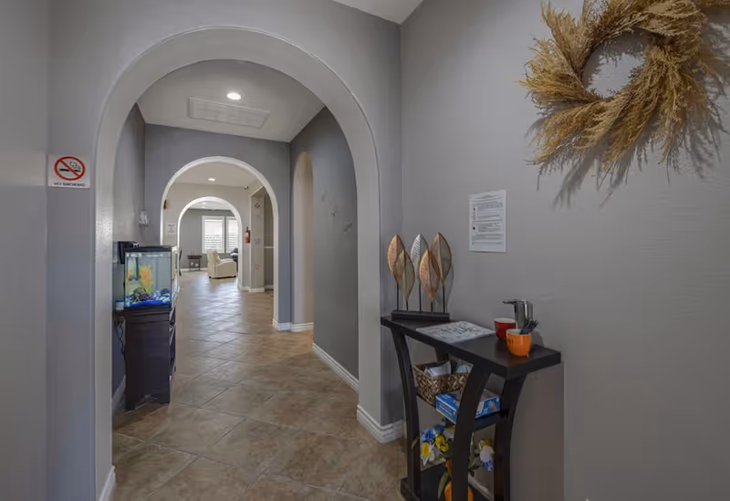 Hallway in a senior living facility with arched doorways and a small fish tank.