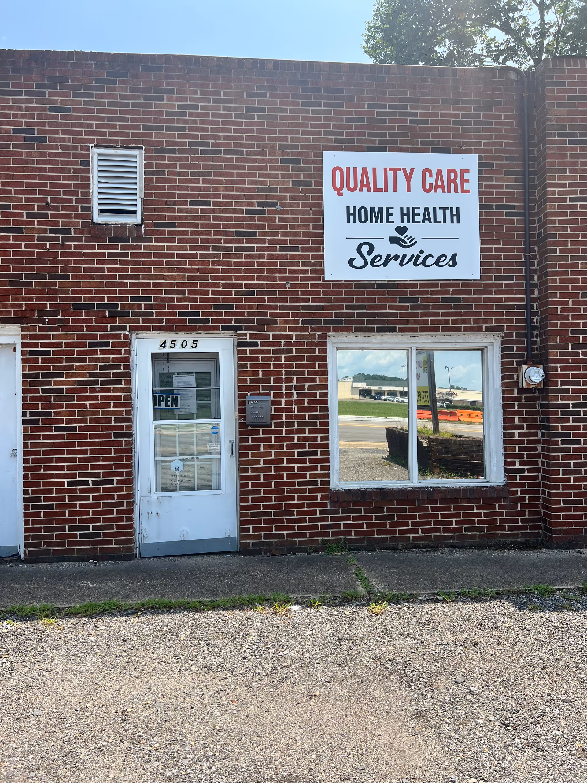 Brick building front with a Quality Care Home Health Services sign and open door