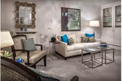 Cozy living room with sofa, chairs, coffee table, lamps, and framed artwork.