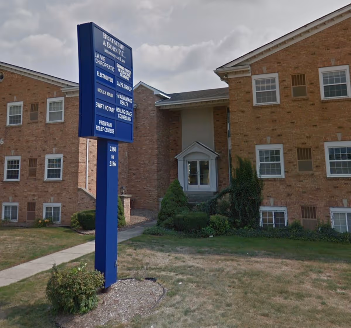 Brick senior living building with a blue directory sign at the entrance.