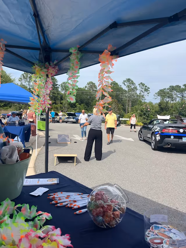 Outdoor senior living event with tents, tables, decorations, and people in a parking lot.