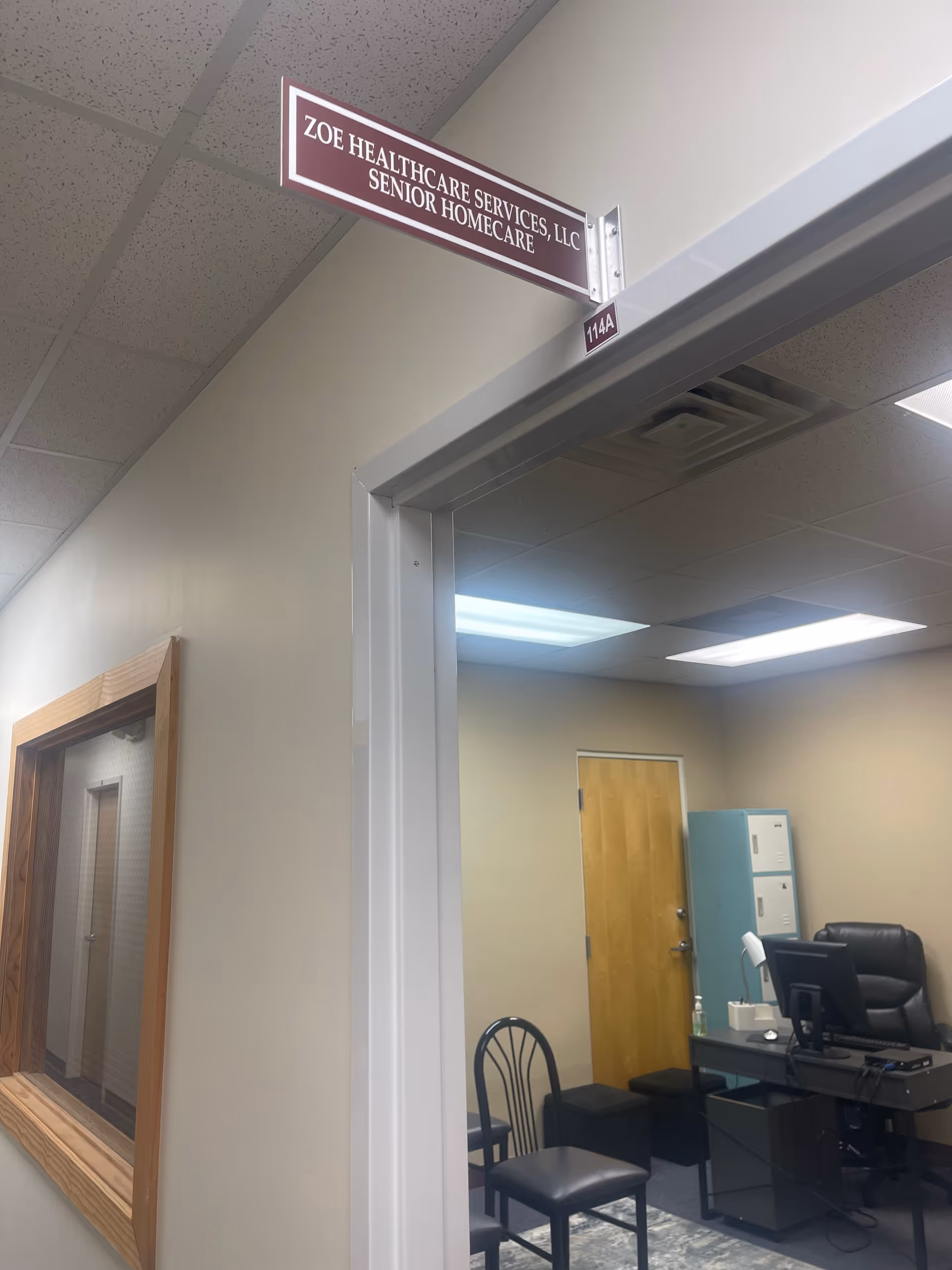 Interior office area of a senior care facility with a doorway, desk, and sign.