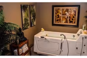 Accessible white bathtub with safety rails in a warmly lit bathroom.