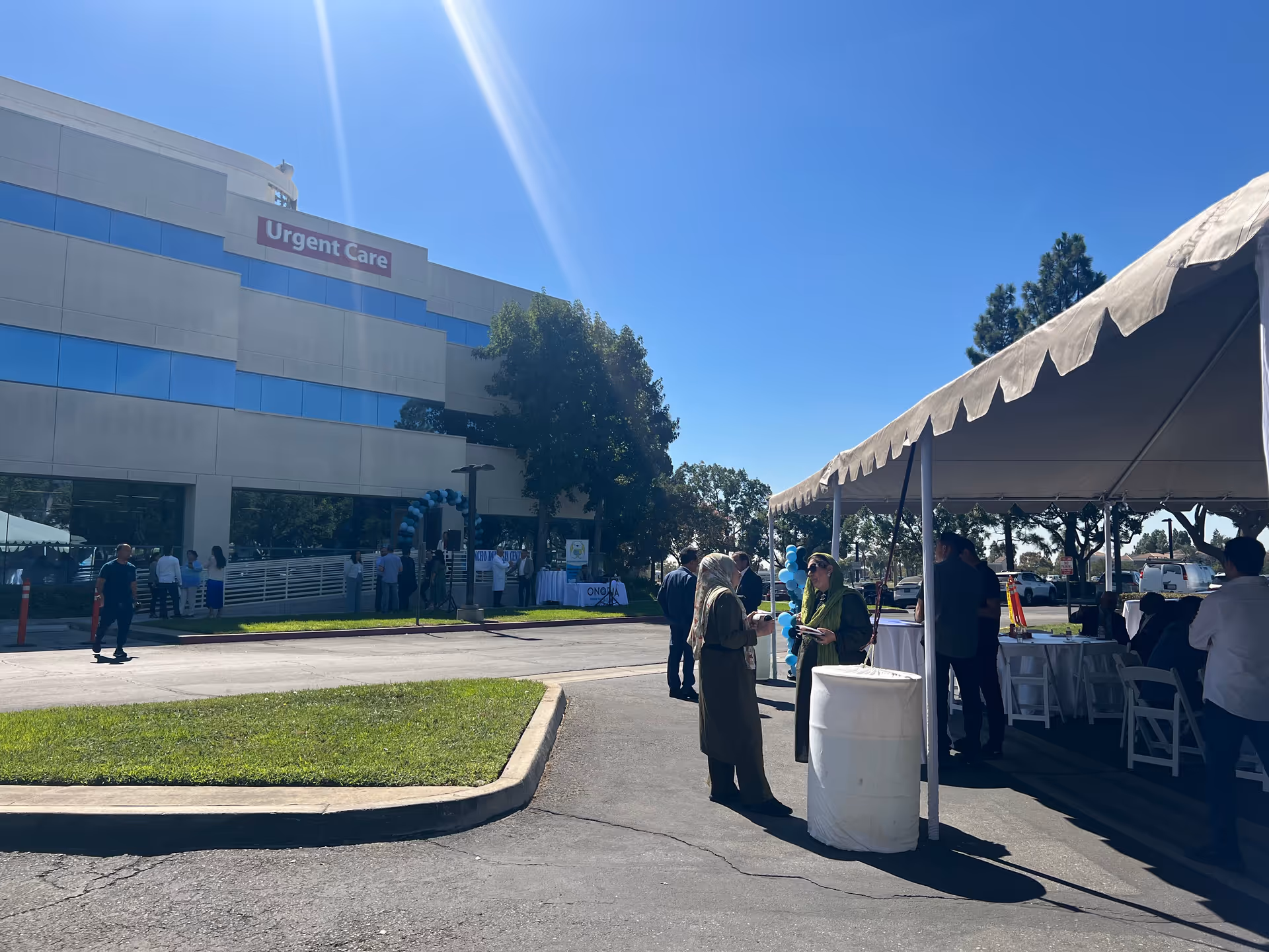 Exterior view of a medical facility with an outdoor tent, attendees, and tables set up.