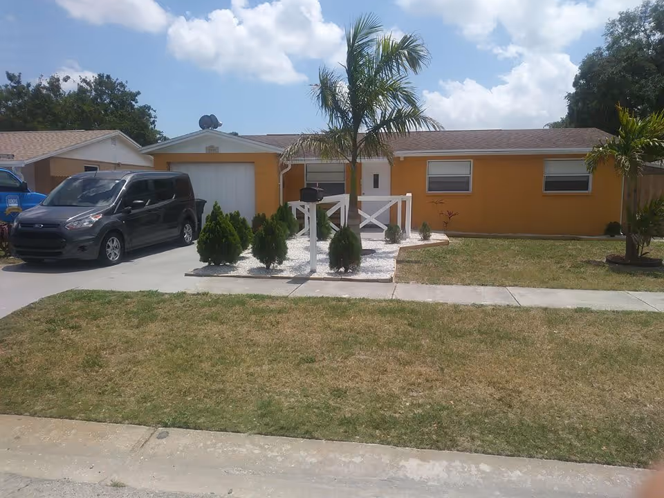 Glade Garden senior living facility front yard with palm trees and a white gate