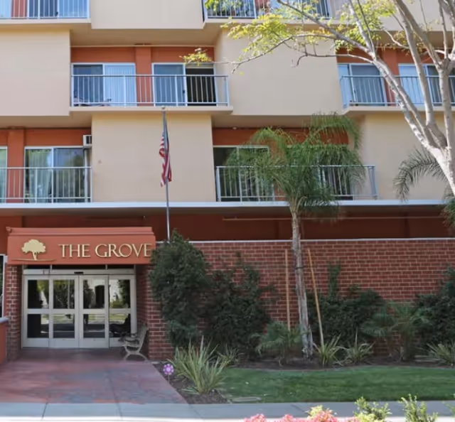 Exterior view of The Grove senior living building entrance with landscaping.