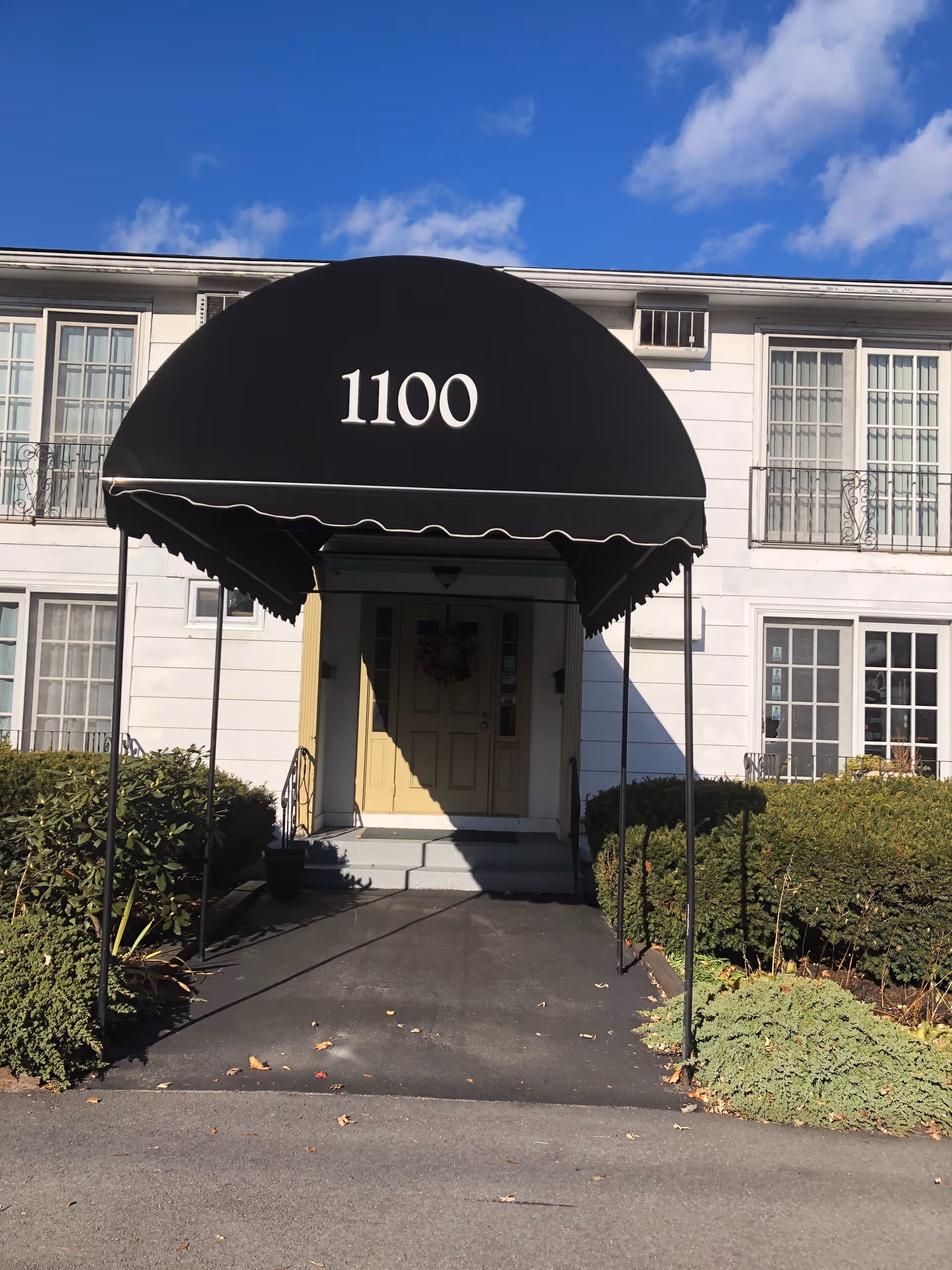 Front entrance of a senior living building with a black canopy marked 1100.