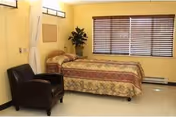 Two single beds with floral bedding, a chair, and a window with blinds in a bedroom.