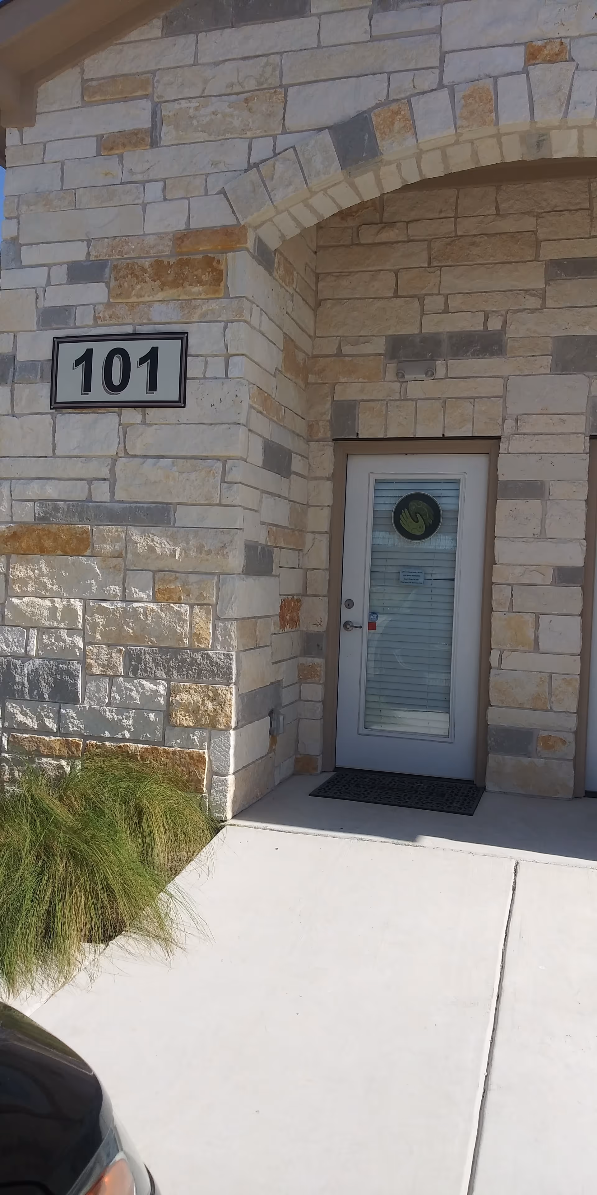 Stone exterior of a building with a glass door labeled 101 at the entrance.