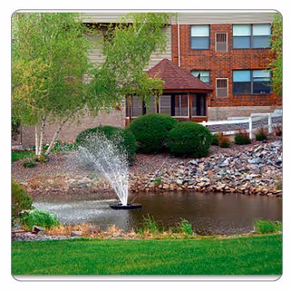 Exterior view of Epiphany Assisted Living with a landscaped pond, fountain, and brick building.