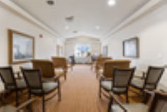 Long, softly lit waiting area with chairs facing a distant reception desk.