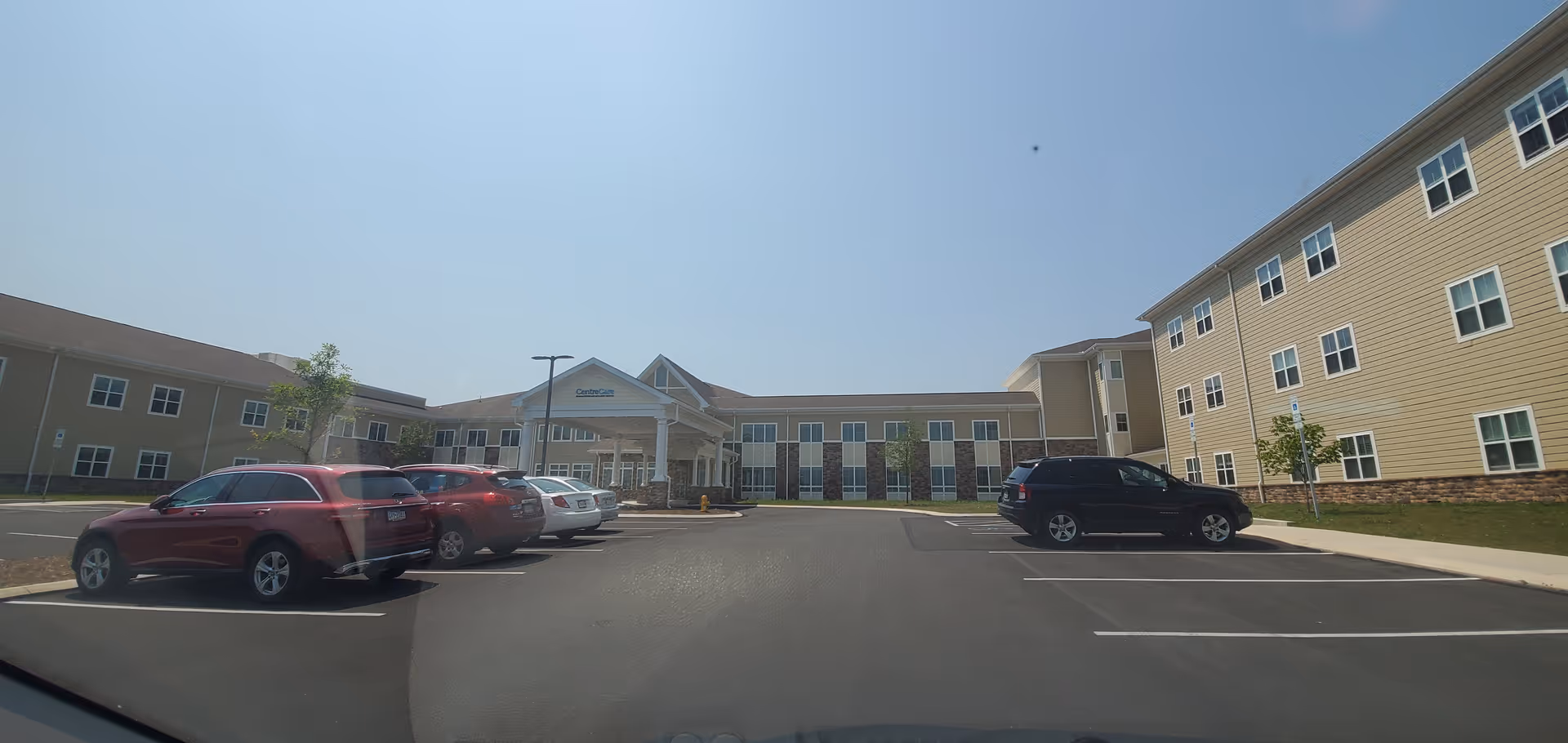 Exterior view of Centre Care facility with a parking lot and cars in front.