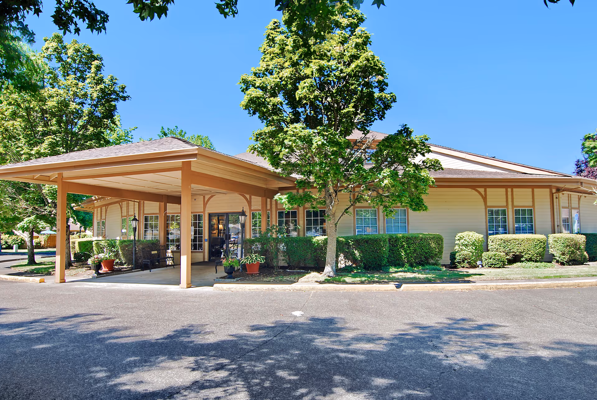 Single-story senior living facility with a covered entrance, parking, and manicured landscaping.