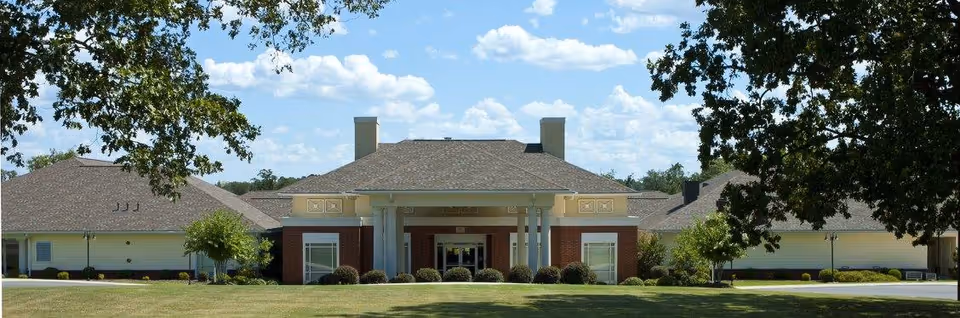 Front exterior view of Mt. Carmel Community Benton building with a large lawn and trees in the foreground under a partly cloudy sky.
