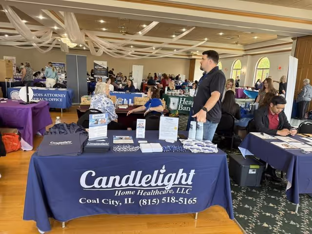Indoor event hall with multiple vendor booths and a prominent Candlelight Home Healthcare table.
