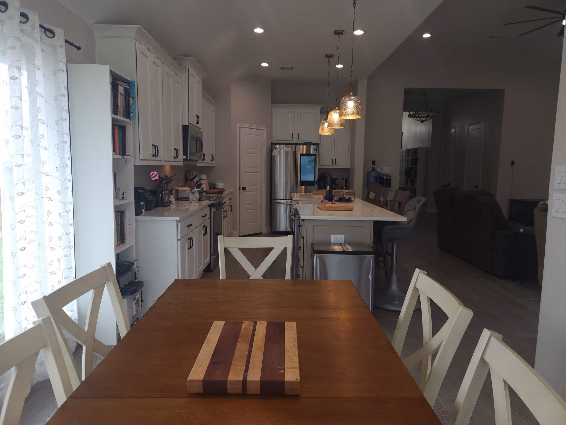 Open-concept kitchen and dining area with white cabinets, island, and wooden dining table.