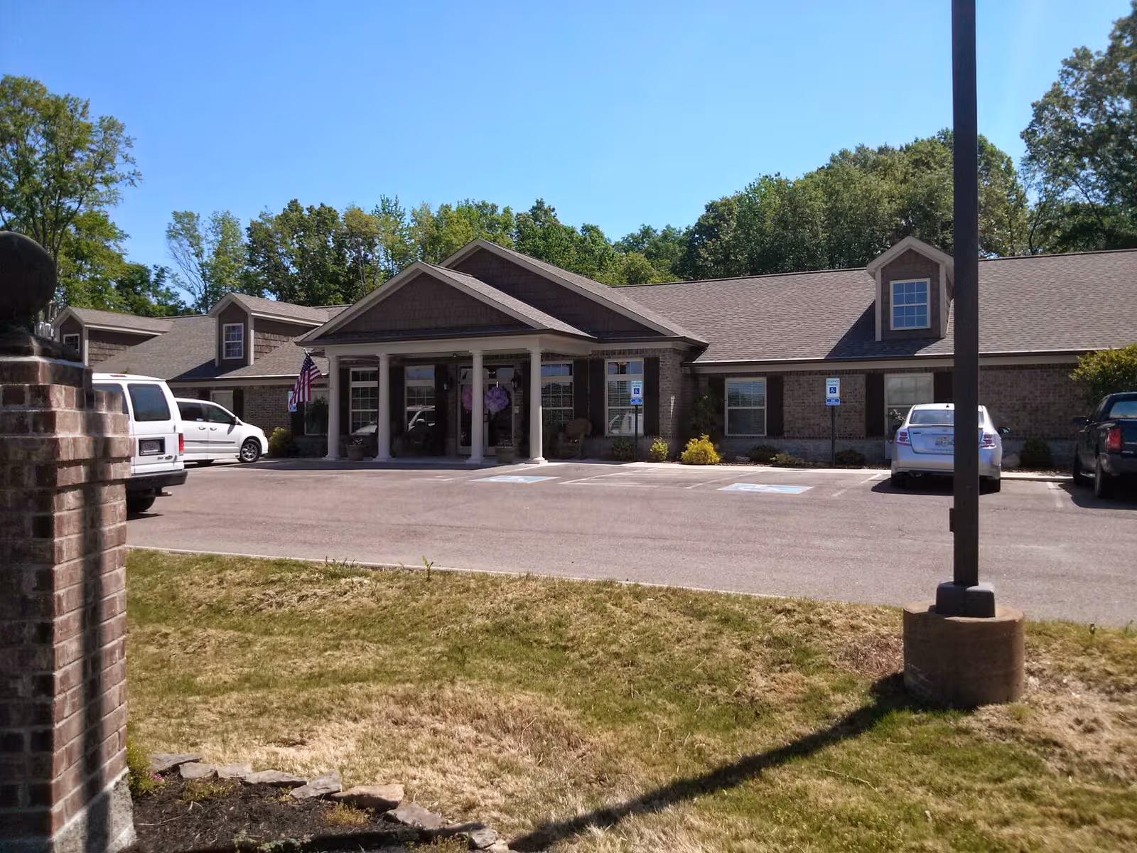 Single-story brick building housing an assisted living center with a covered entrance and parking.