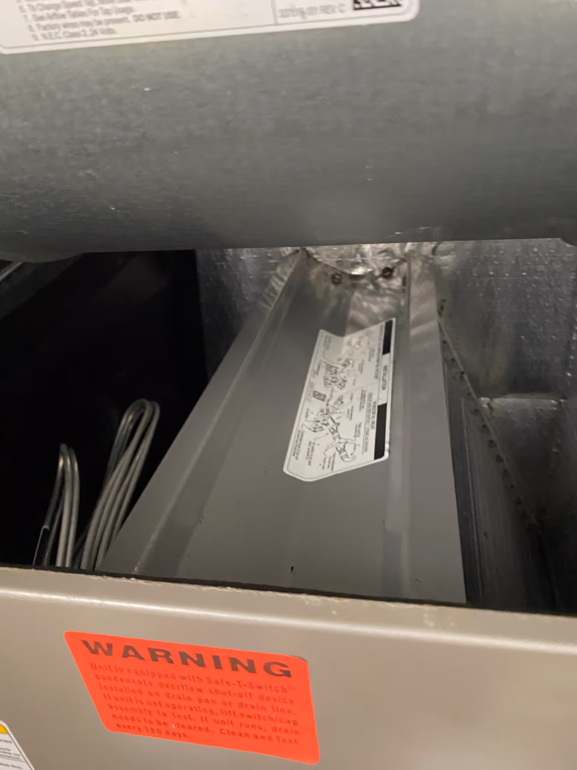 Close-up of HVAC unit with red warning sticker in a utility room