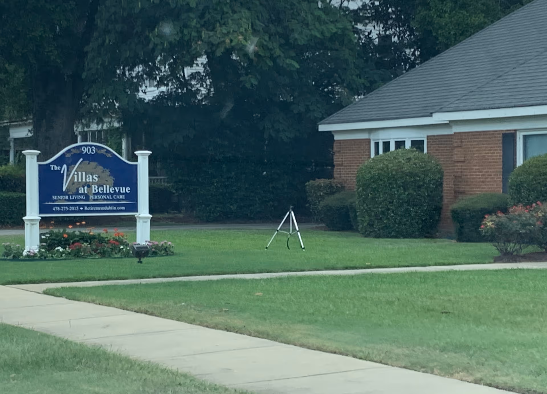 Blue sign for The Villas at Bellevue sits on a manicured lawn beside a brick building.