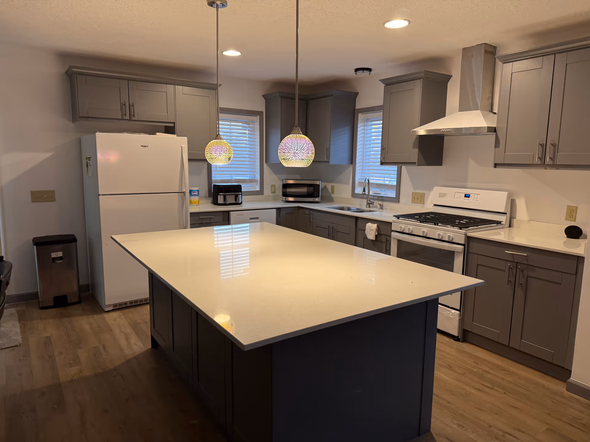 Modern kitchen with gray cabinets, white countertops, a central island, and stainless appliances.