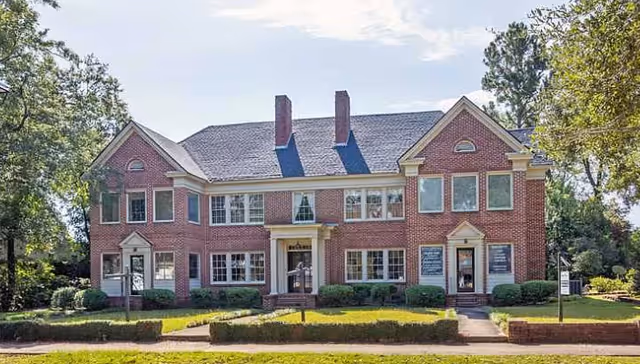 Front view of a red-brick senior living facility with windows and a manicured lawn.