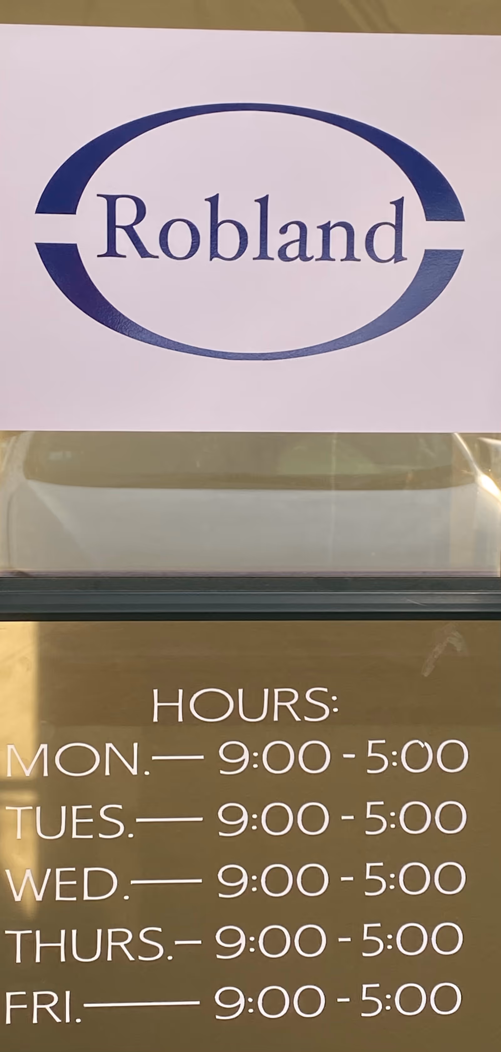 Robland Home Health Care logo sign above glass door with hours listed.