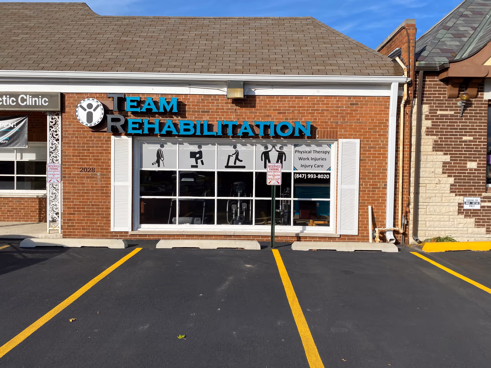 A brick storefront features a teal Team Rehabilitation sign and large display windows.