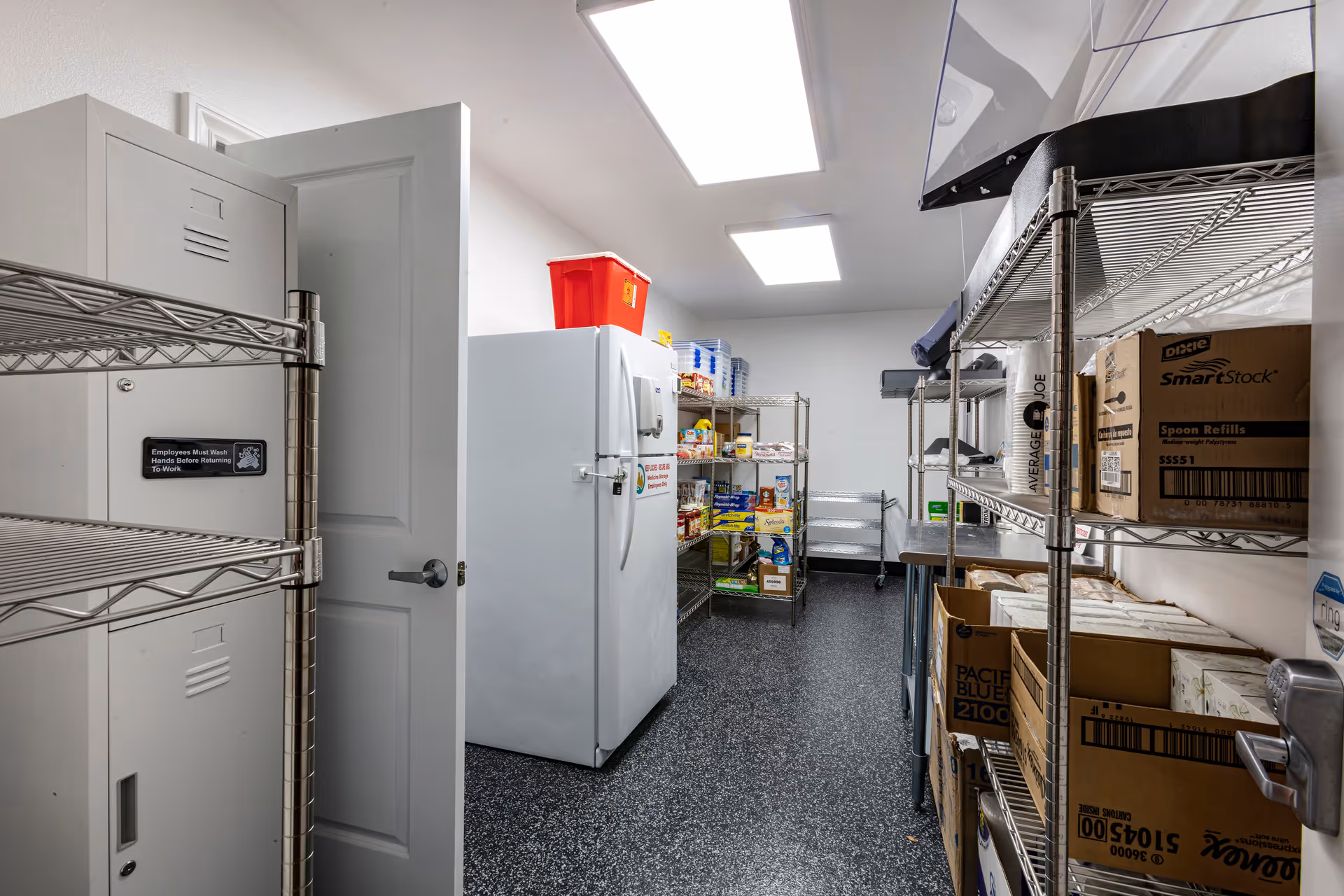 A storage/pantry room with metal shelving stocked with boxes and supplies and a white upright freezer.