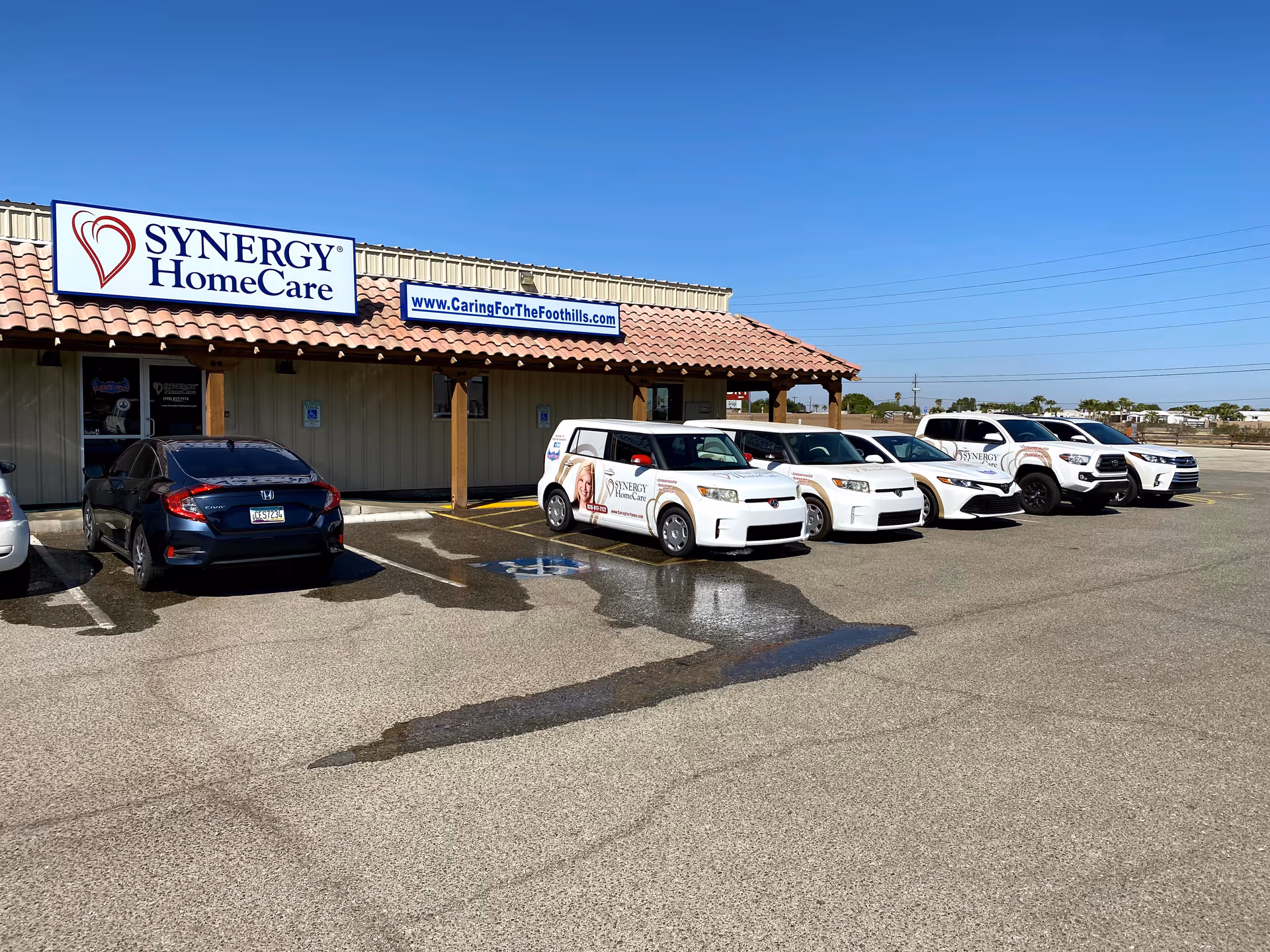 Synergy HomeCare of Yuma storefront with a row of parked cars in the lot.