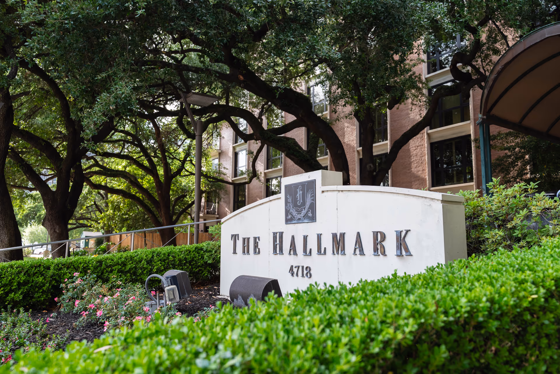 Stone sign reading The Hallmark with surrounding hedges and large trees.