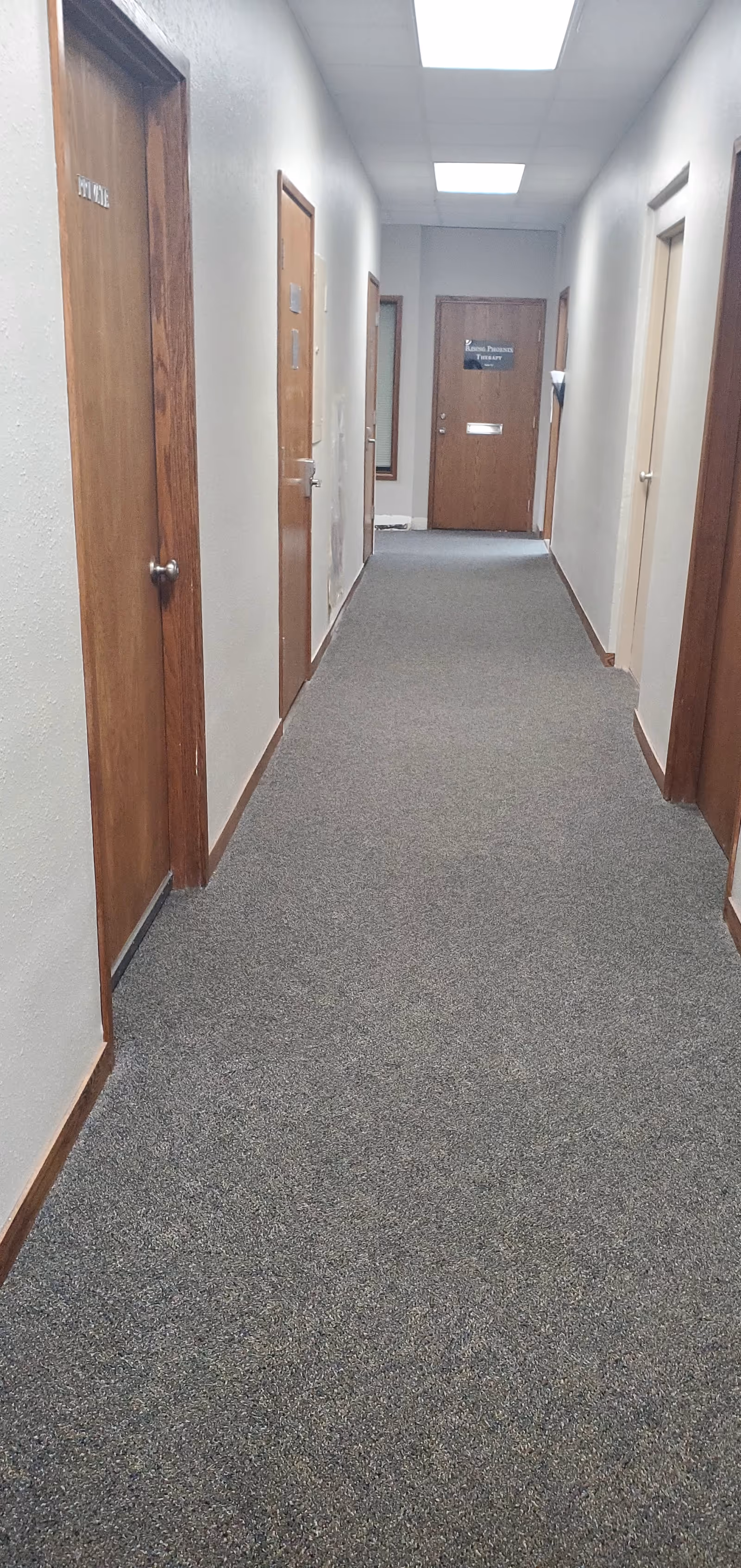 Long interior hallway in a senior living facility with wooden doors along both sides.