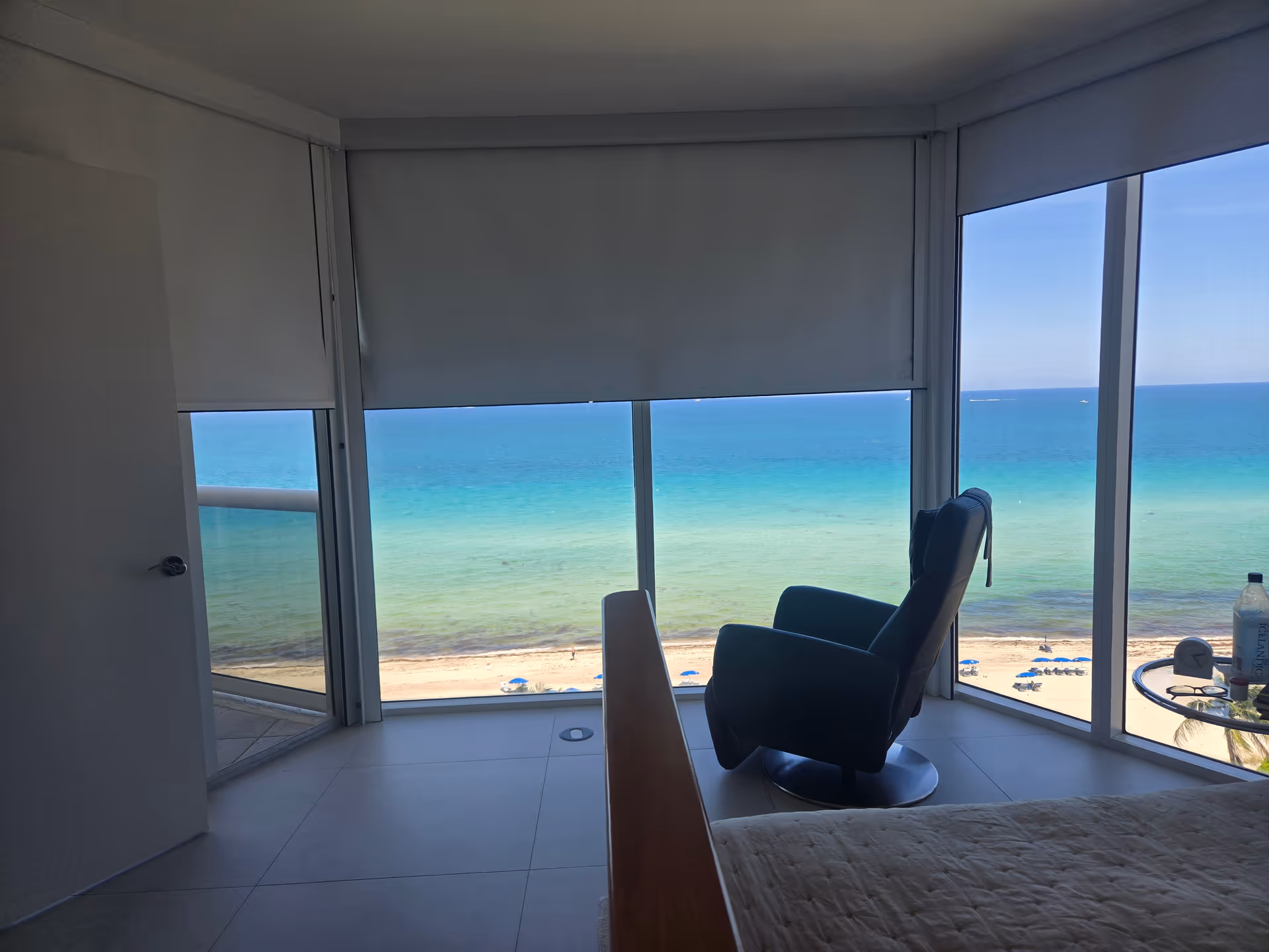 Beachfront bedroom with large windows, ocean view, and a recliner.