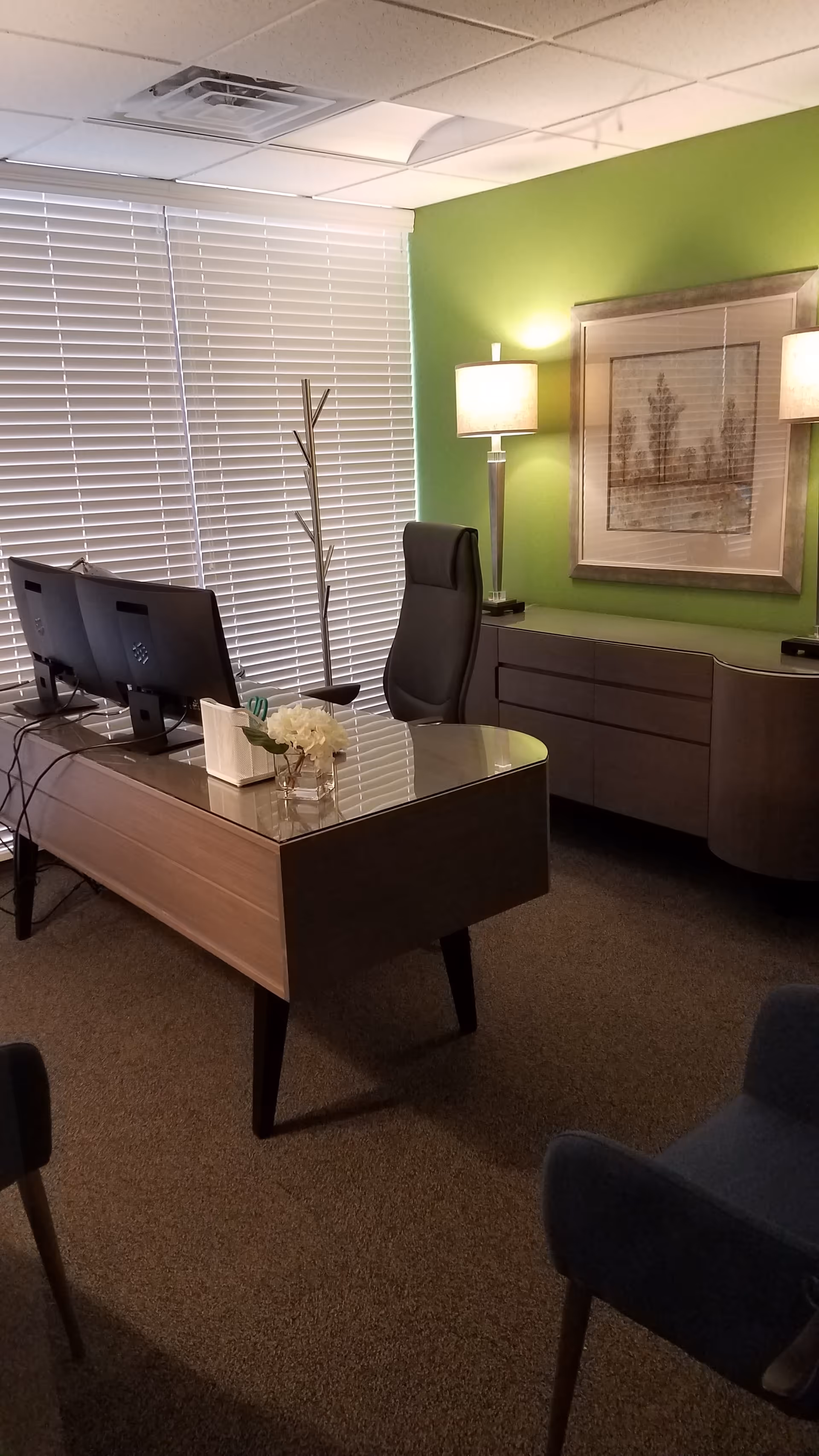 Modern office desk with dual monitors and a green accent wall.
