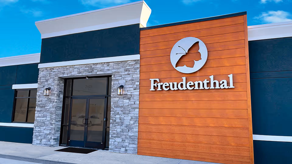 Modern senior living facility exterior with Freudenthal sign and stone facade