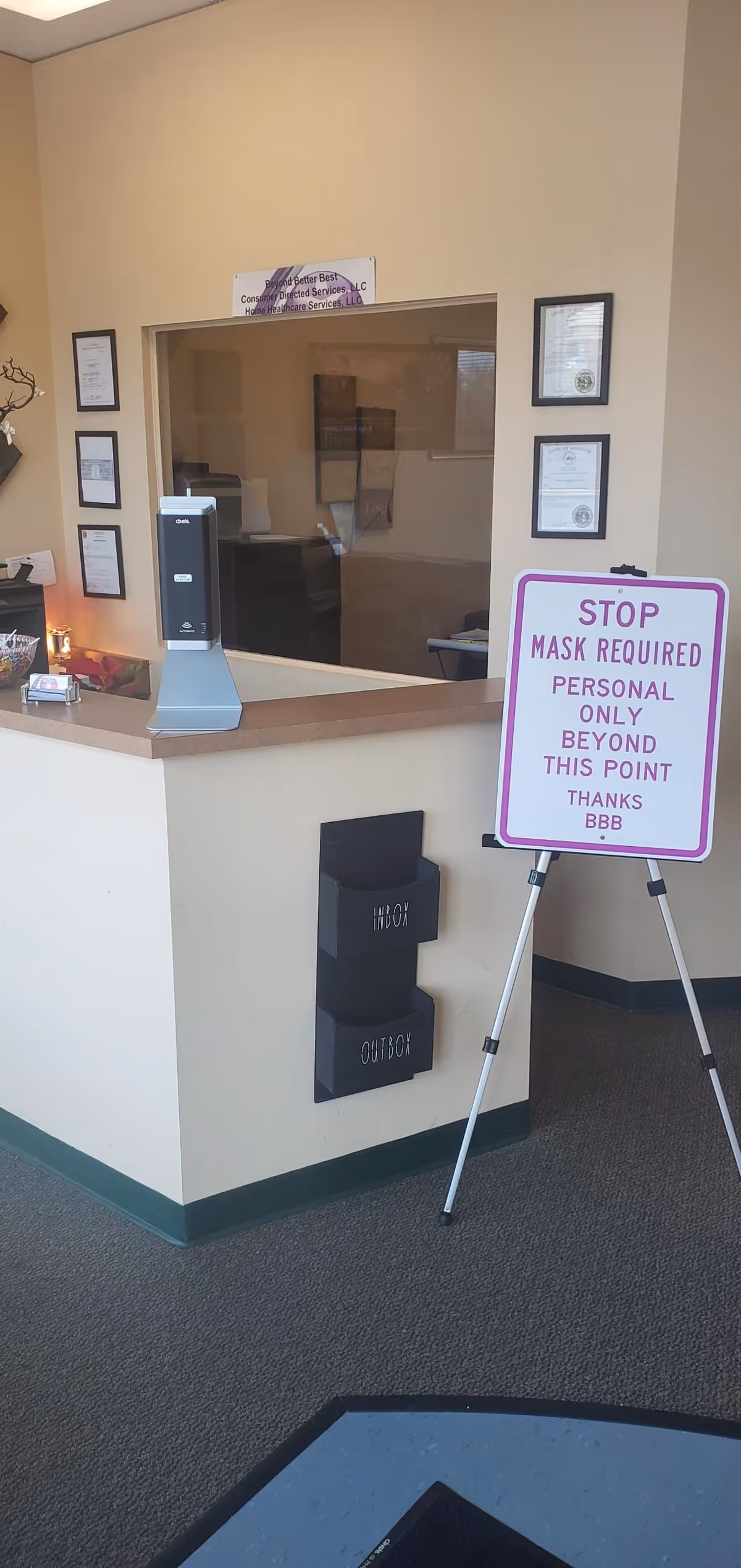 Reception desk area inside a senior living facility with a sign and hand sanitizer.