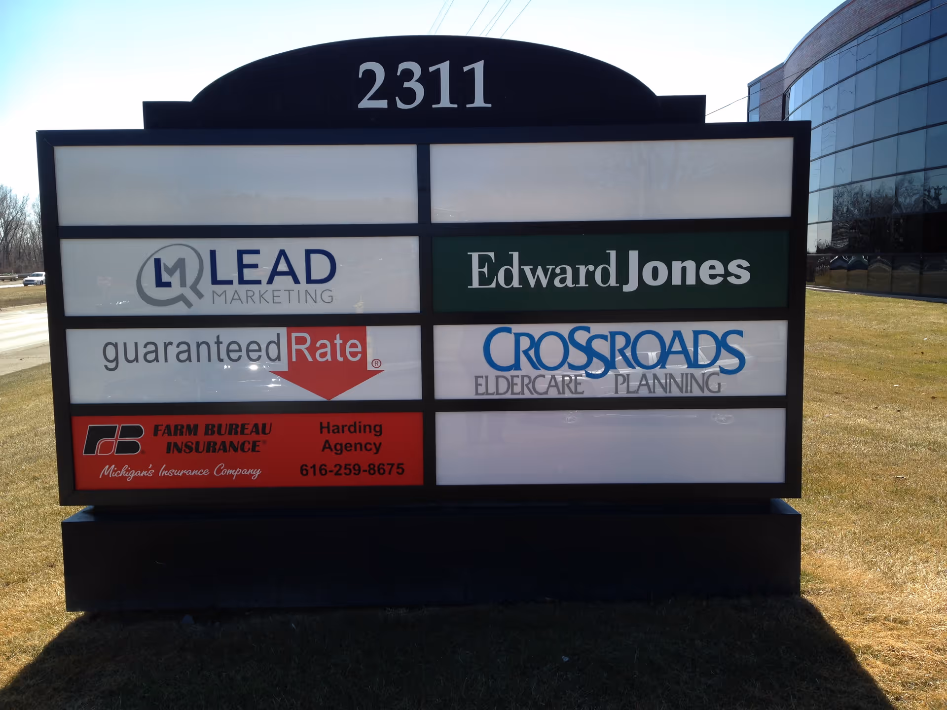 Outdoor building sign with multiple business logos, including Edward Jones and Crossroads Eldercare Planning, 2311.