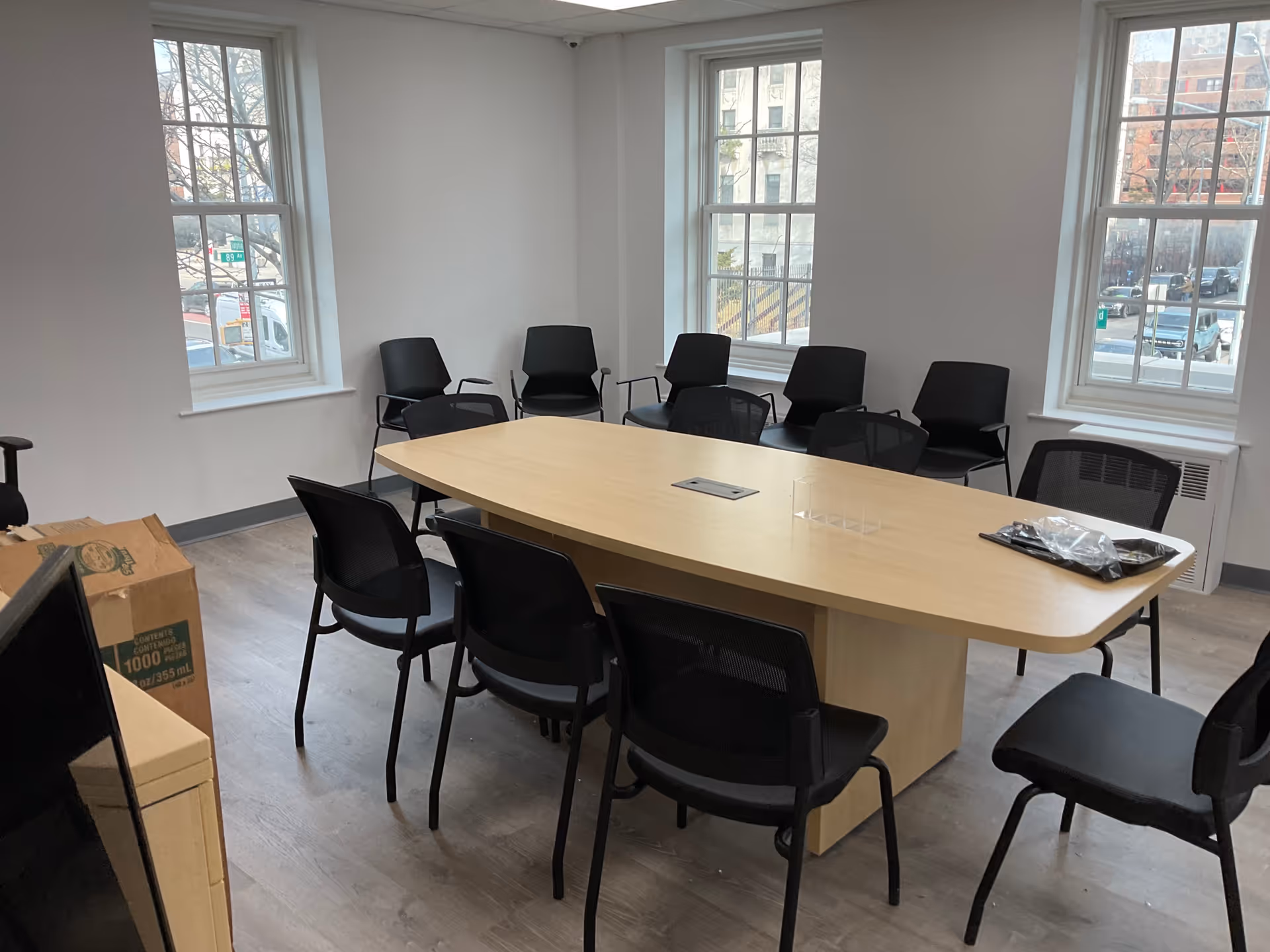 Empty conference room with a large oval table and black chairs near windows.