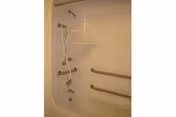 Accessible bathroom features a tub with a handheld shower and grab bars.