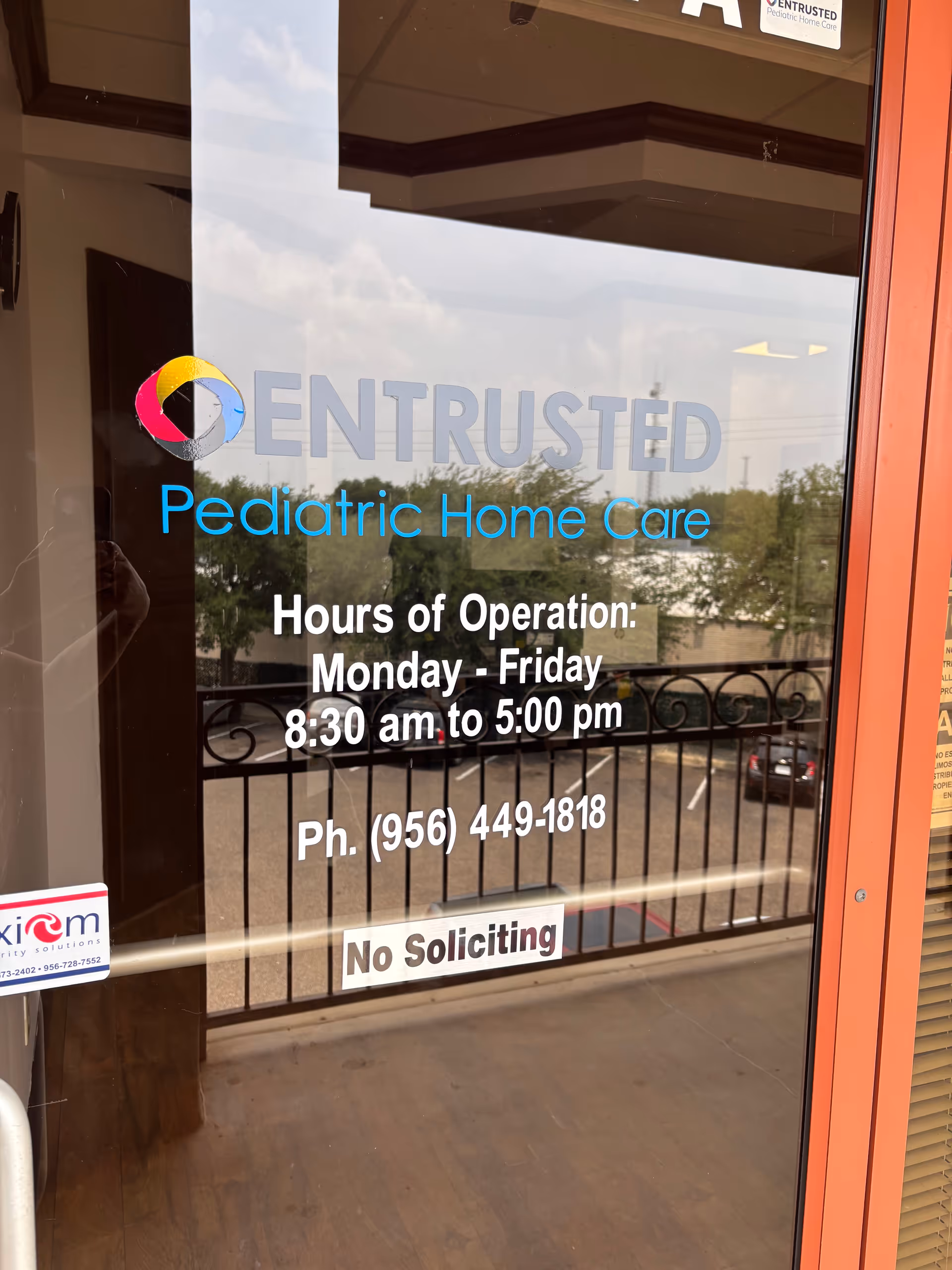 Glass door with Entrusted Pediatric Home Care sign and hours, no people visible.
