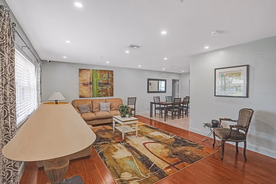 Spacious senior living common area with a sofa, rug, coffee table, and dining table.