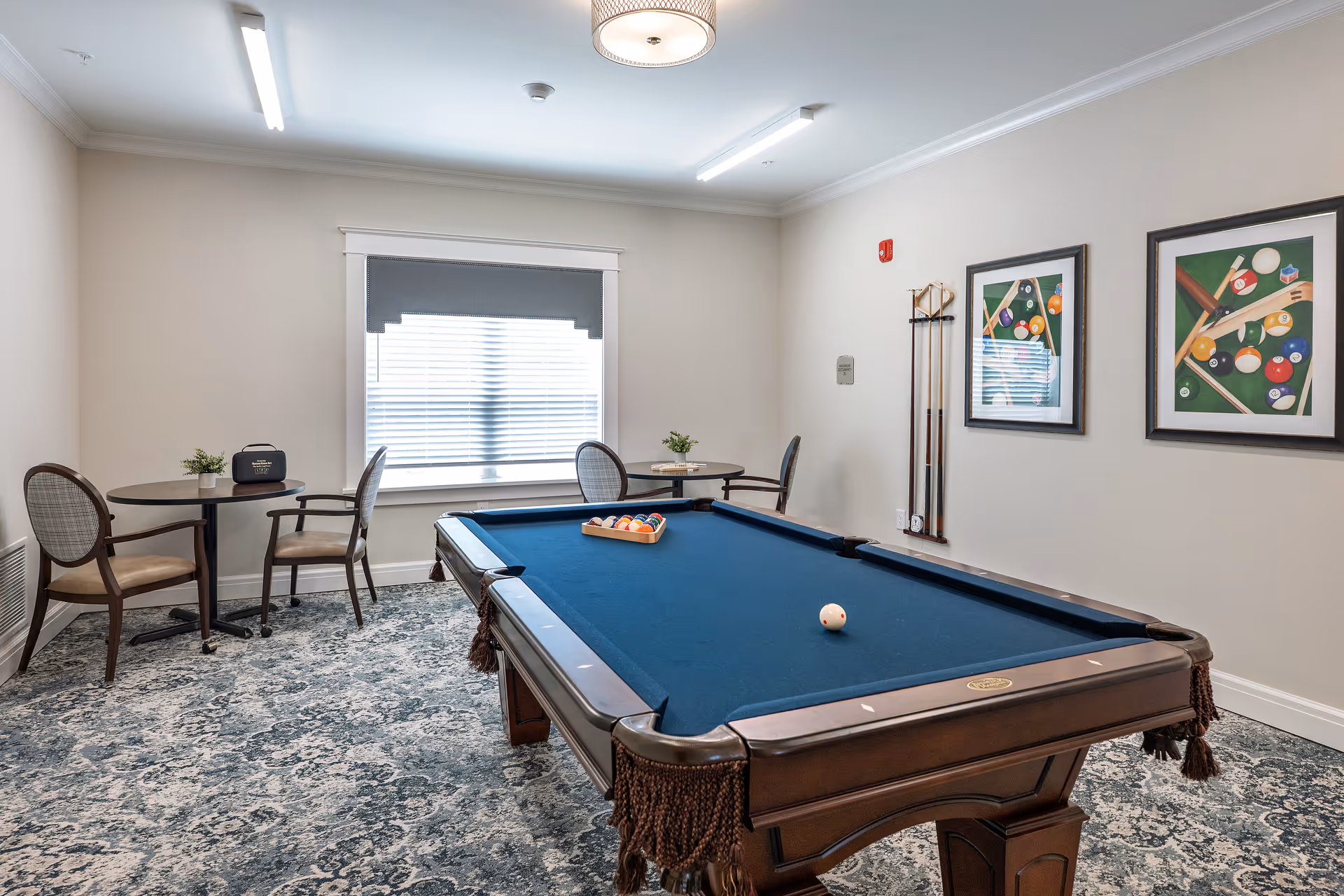 Interior recreation room featuring a pool table, small tables, chairs, and wall art.