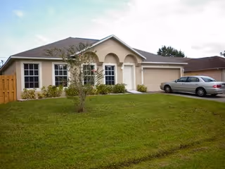 Front view of a single-story senior care facility with a manicured lawn and driveway.