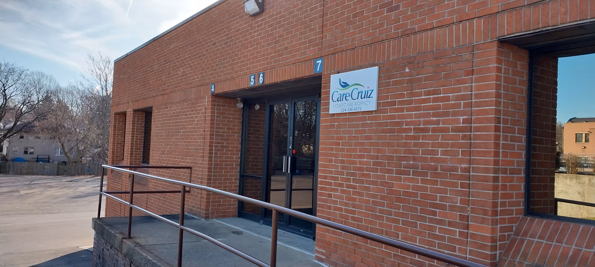 Brick facility entrance with CareCruiz sign and numbered doors 4, 5, 6, 7, ramp, and windows.