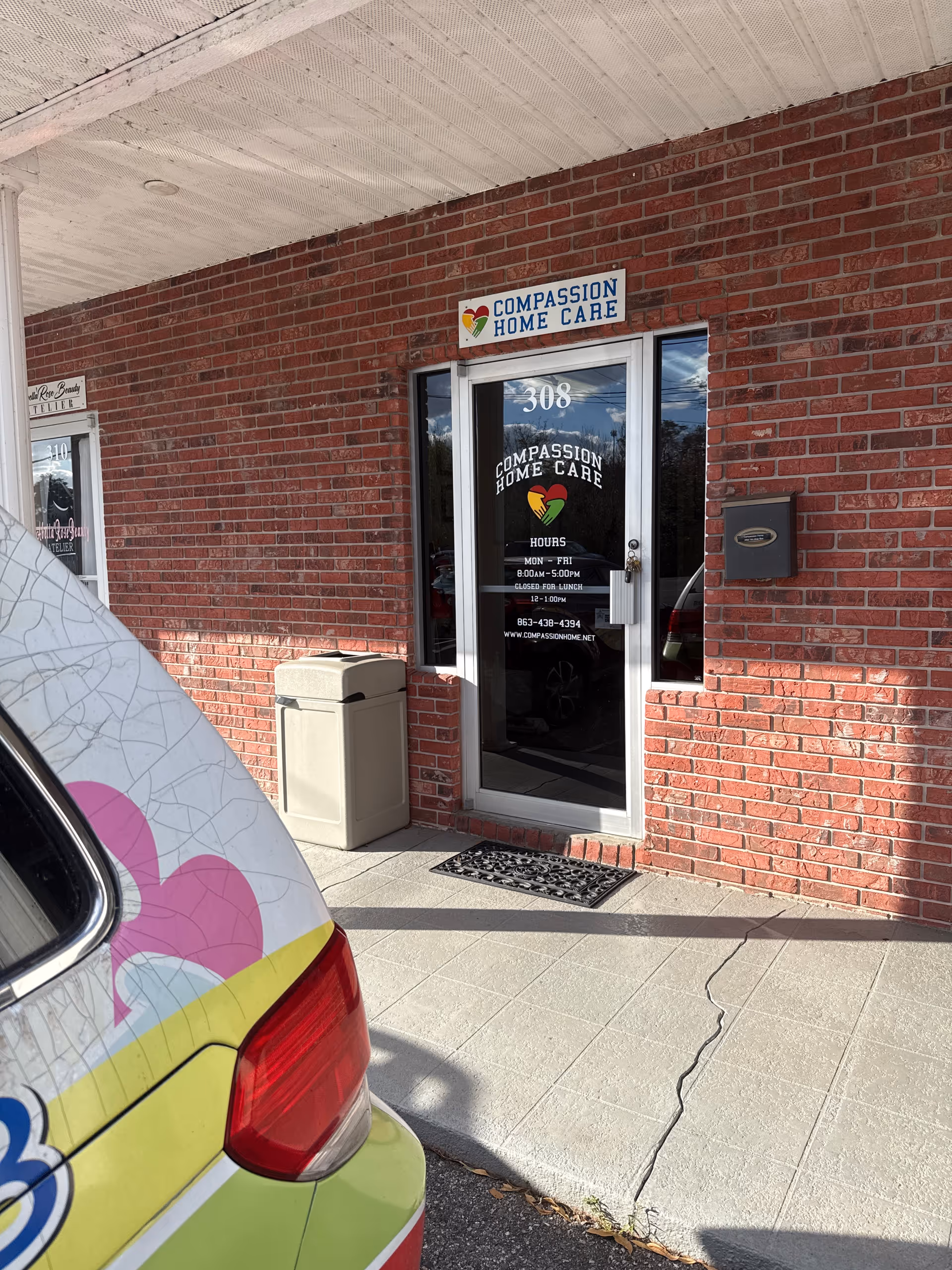 Brick building entrance for Compassion Home Care with sign and ambulance nearby.
