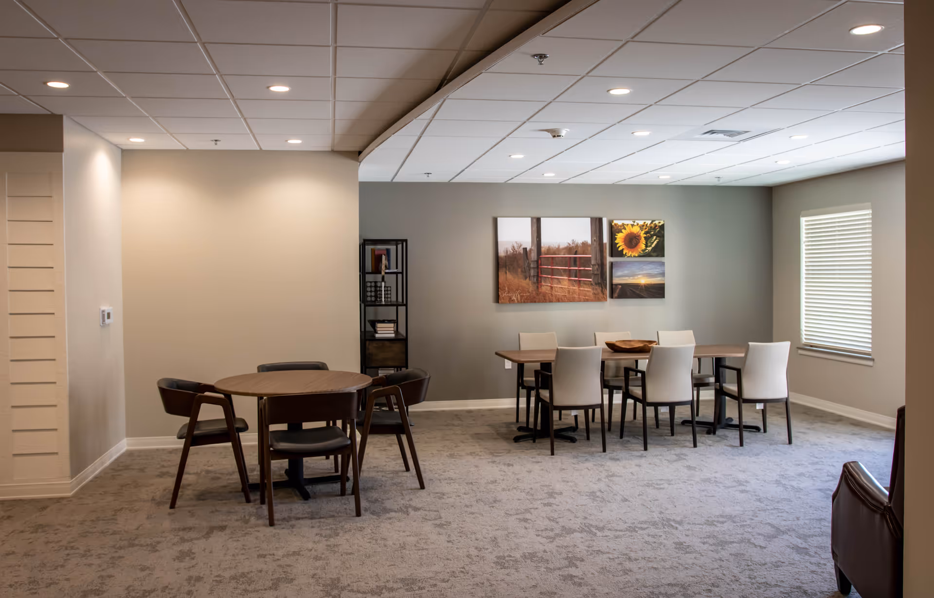 Interior communal dining area with two tables, chairs, and wall artwork.