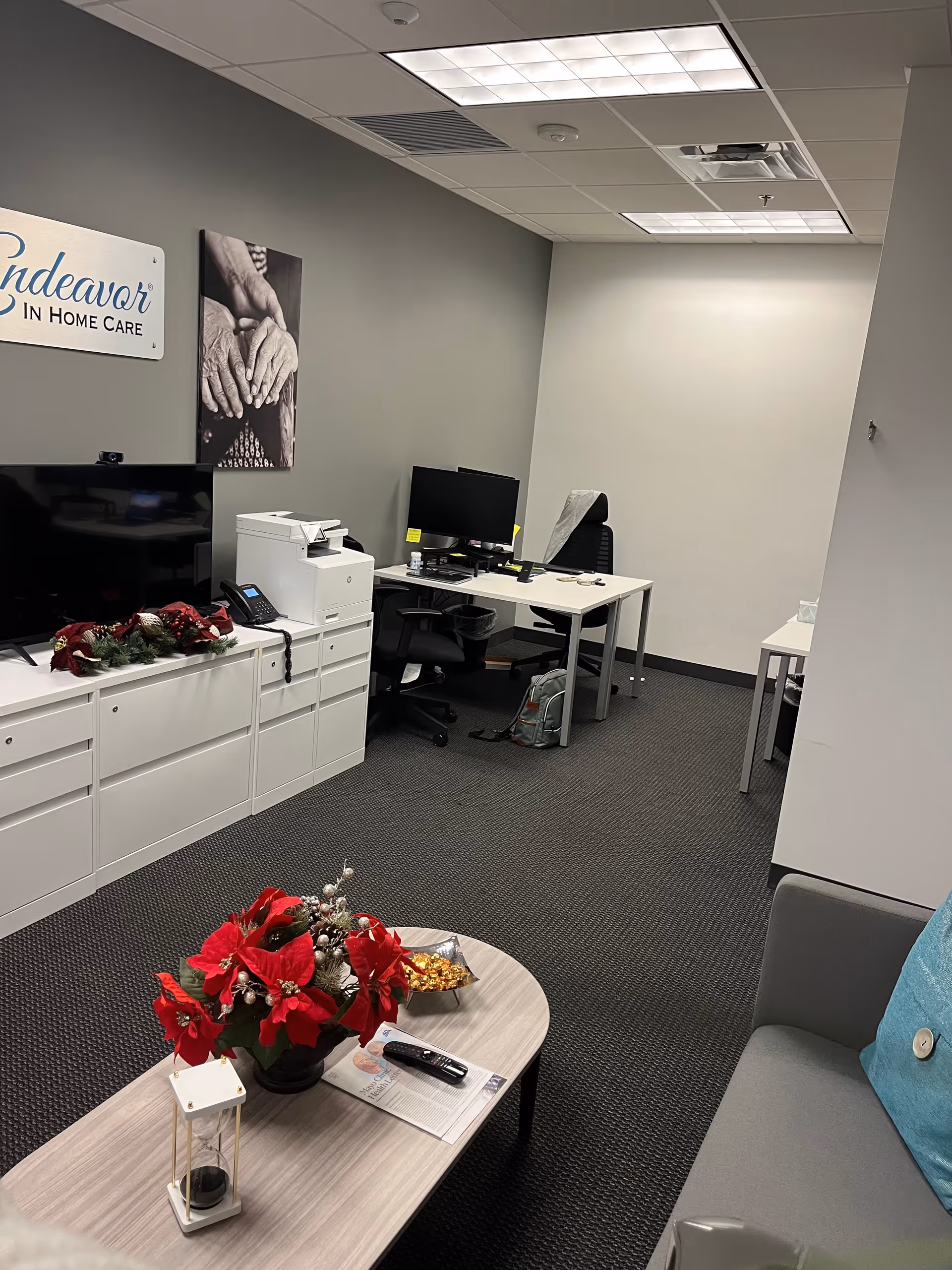 Office reception area for Endeavor In Home Care with desks, printers, and red flowers.