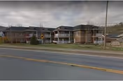 Row of brick senior living buildings across a street with sidewalks.