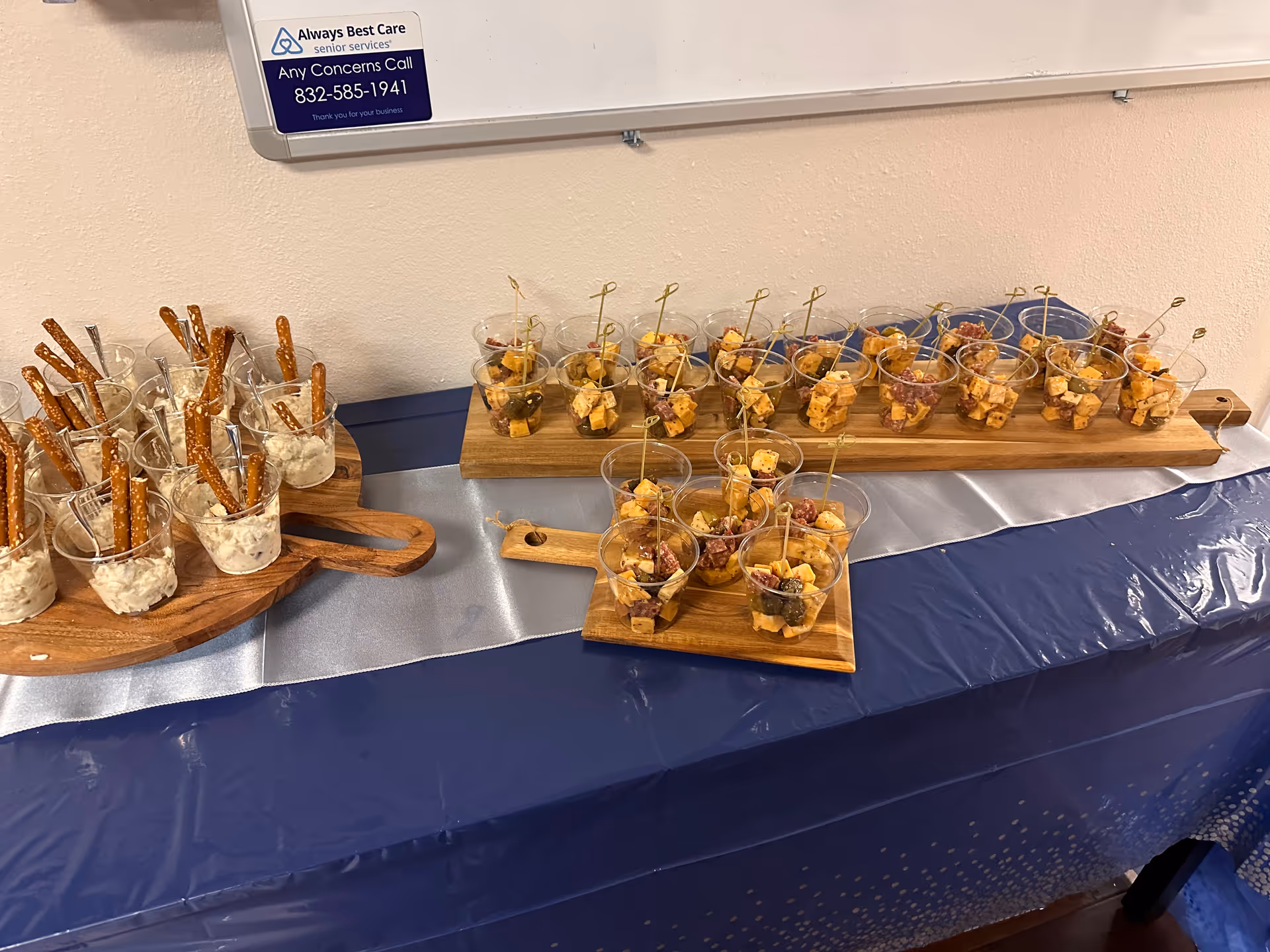 Assorted bite-sized snacks in cups on wooden boards at an indoor facility.