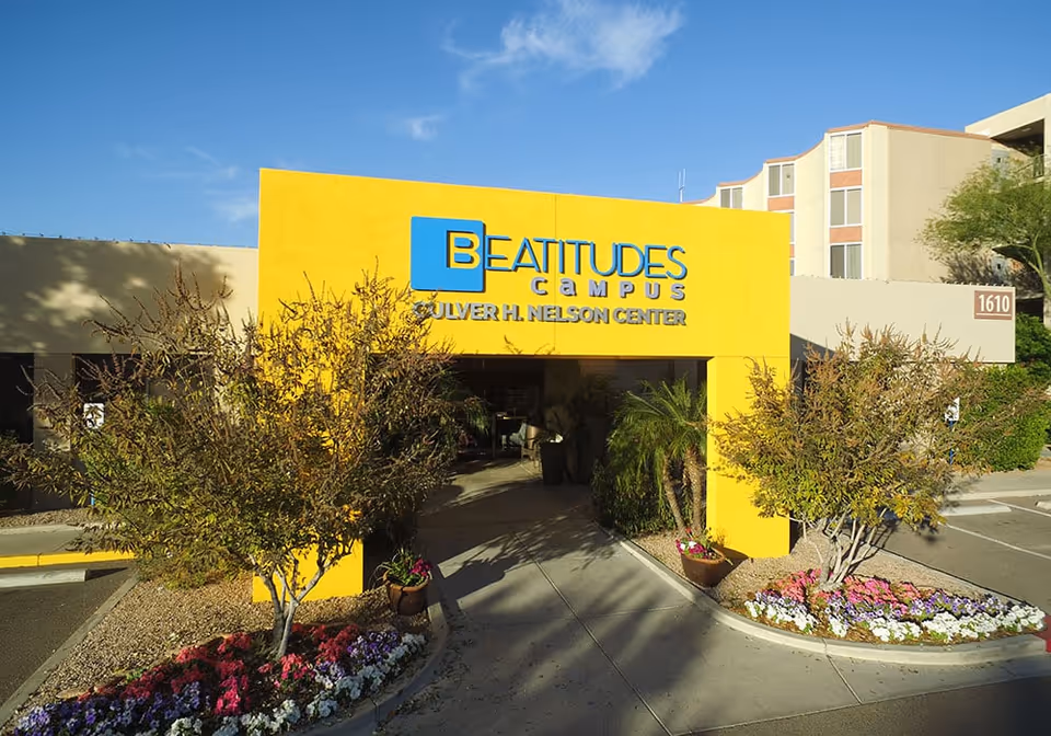 A bright yellow building entrance labeled Beatitudes Campus with landscaping.